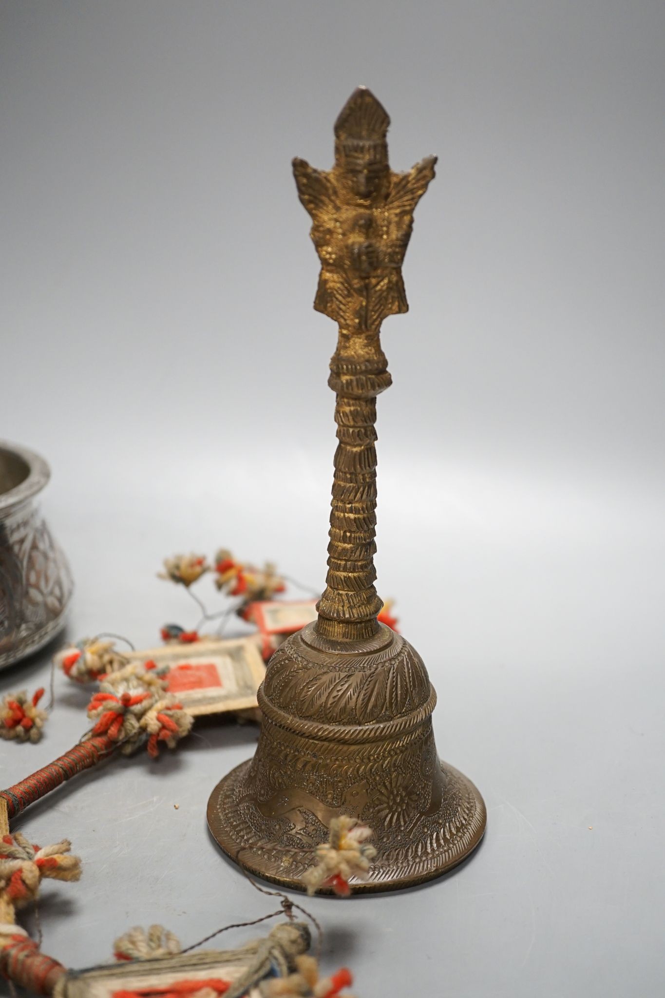 A Himalayan brass bell and bowl, a woolwork finial, 43 cm high, an Islamic tinned metal censer (4)